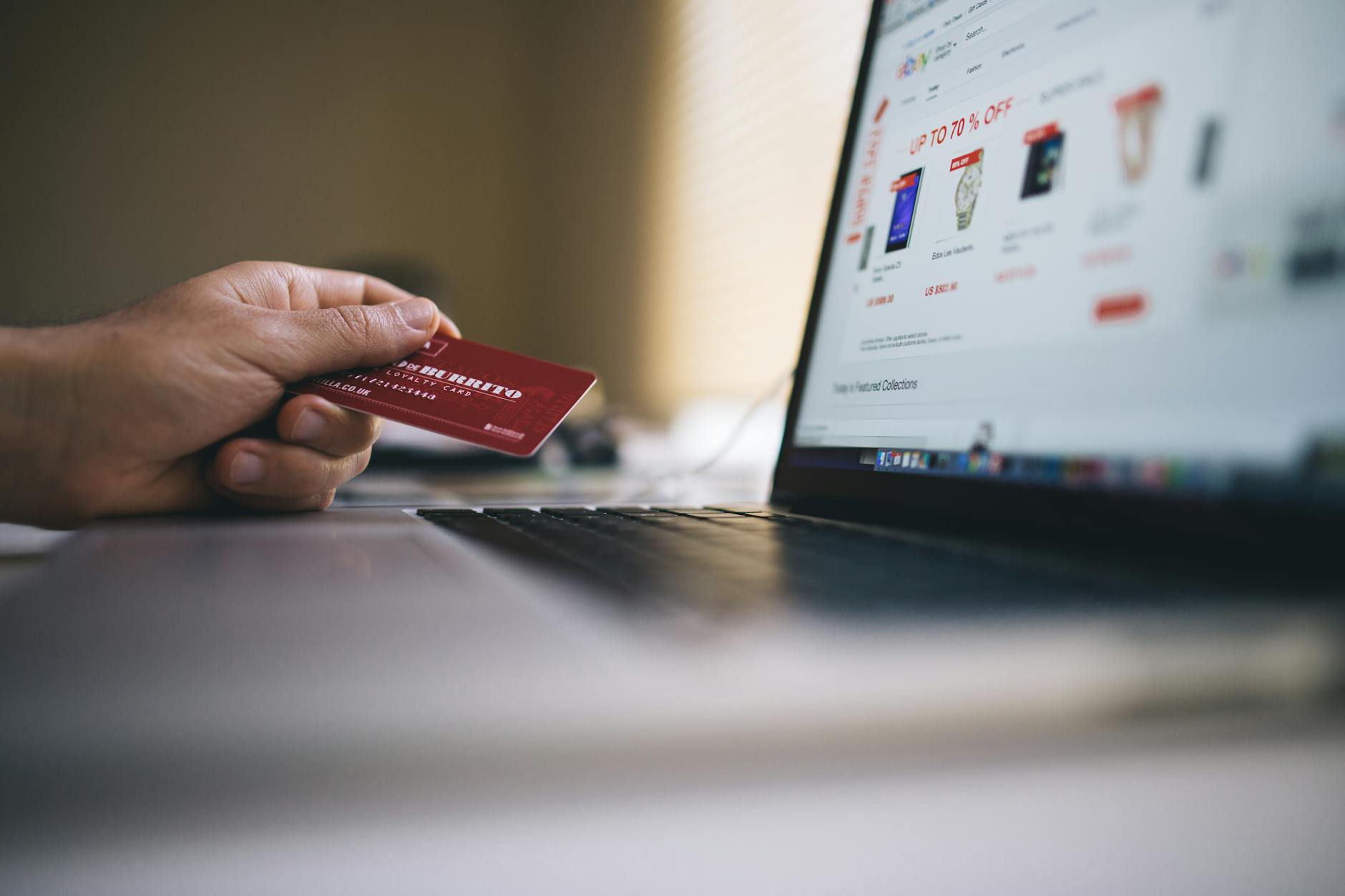 Personne tenant une carte bancaire devant un ordinateur