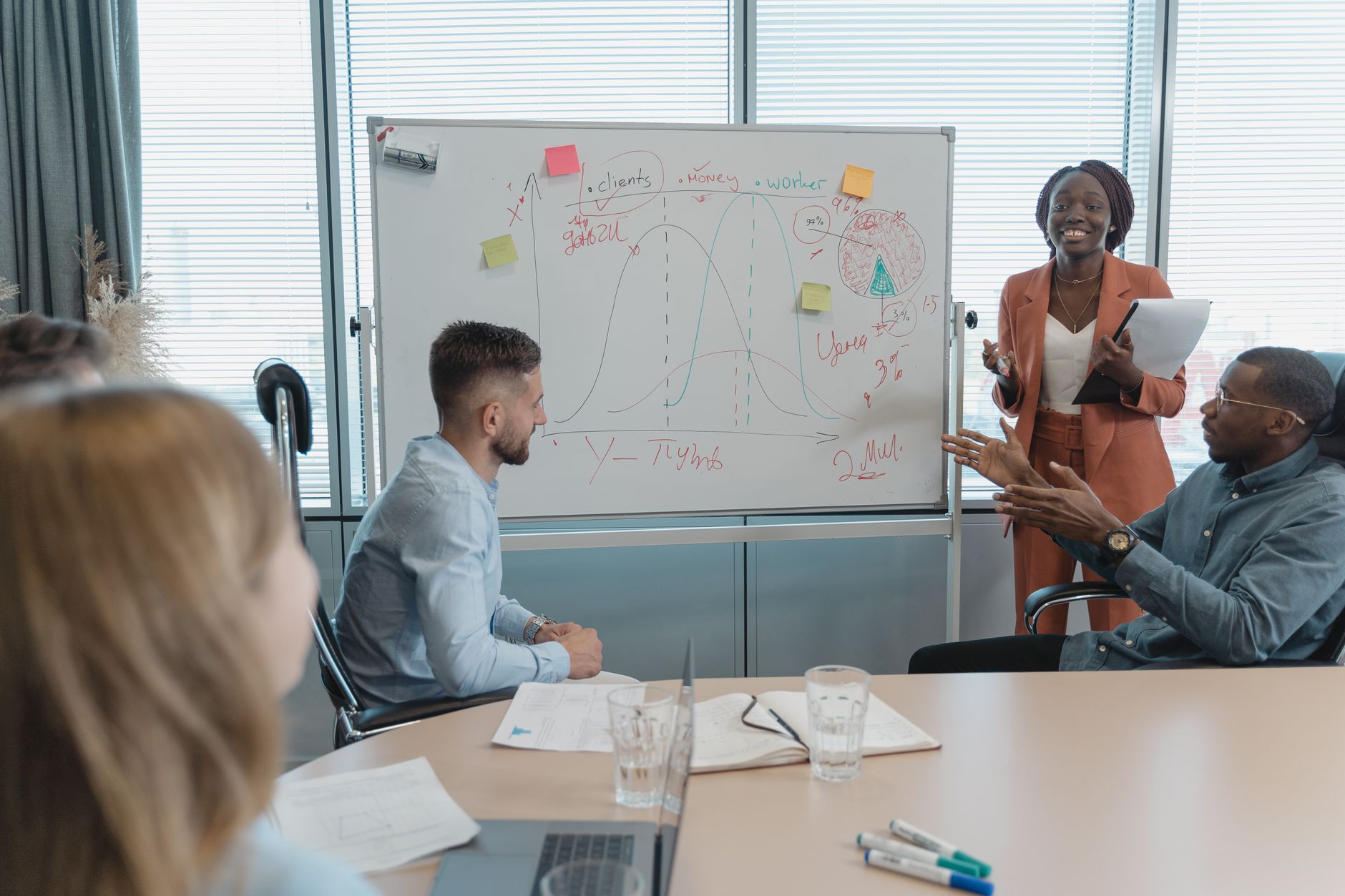 Une équipe pluridisciplinaire discute d'une stratégie marketing autour d'un tableau blanc en salle de réunion