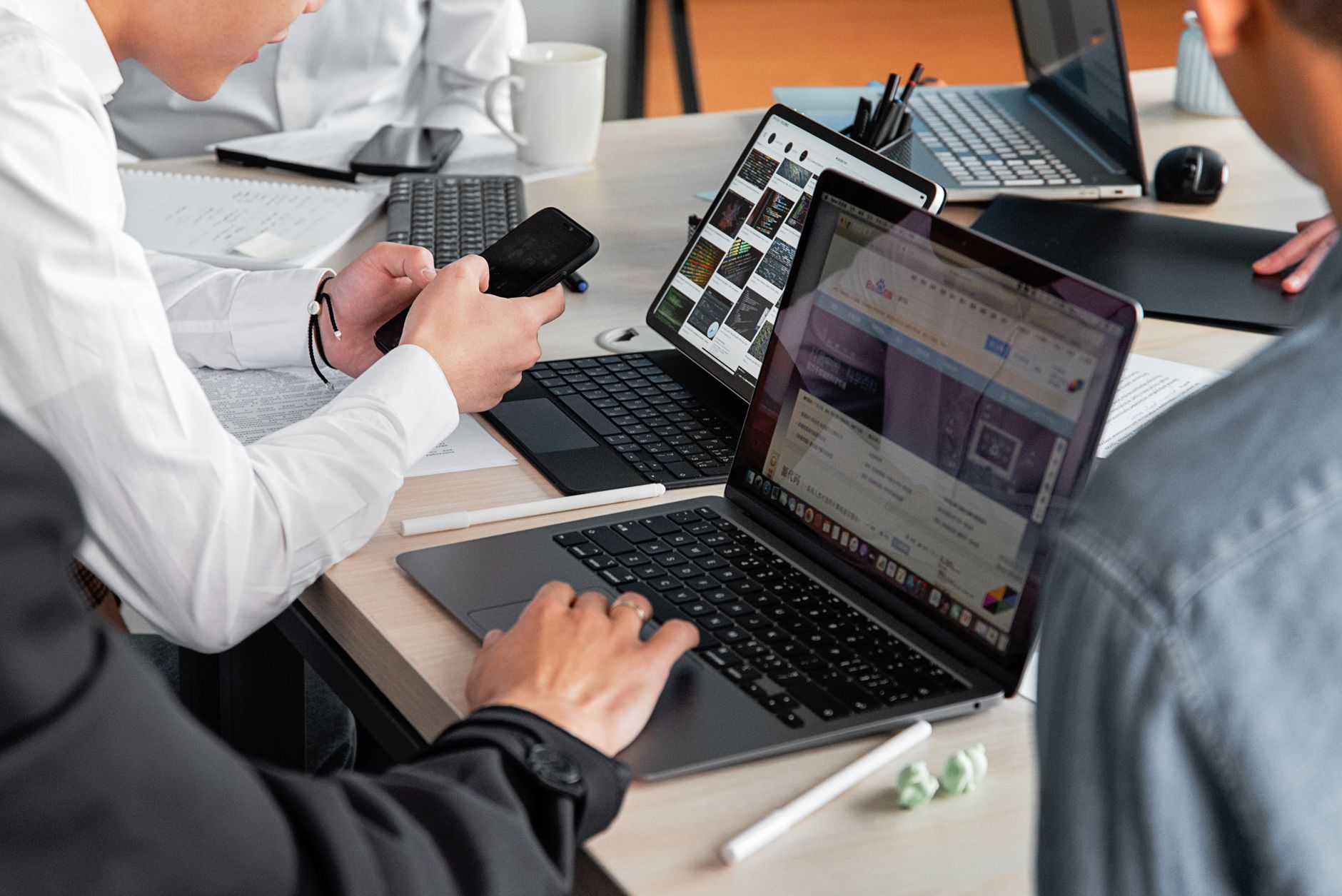 Deux personnes comparent des interfaces sur plusieurs écrans et une tablette pour choisir un outil emailing