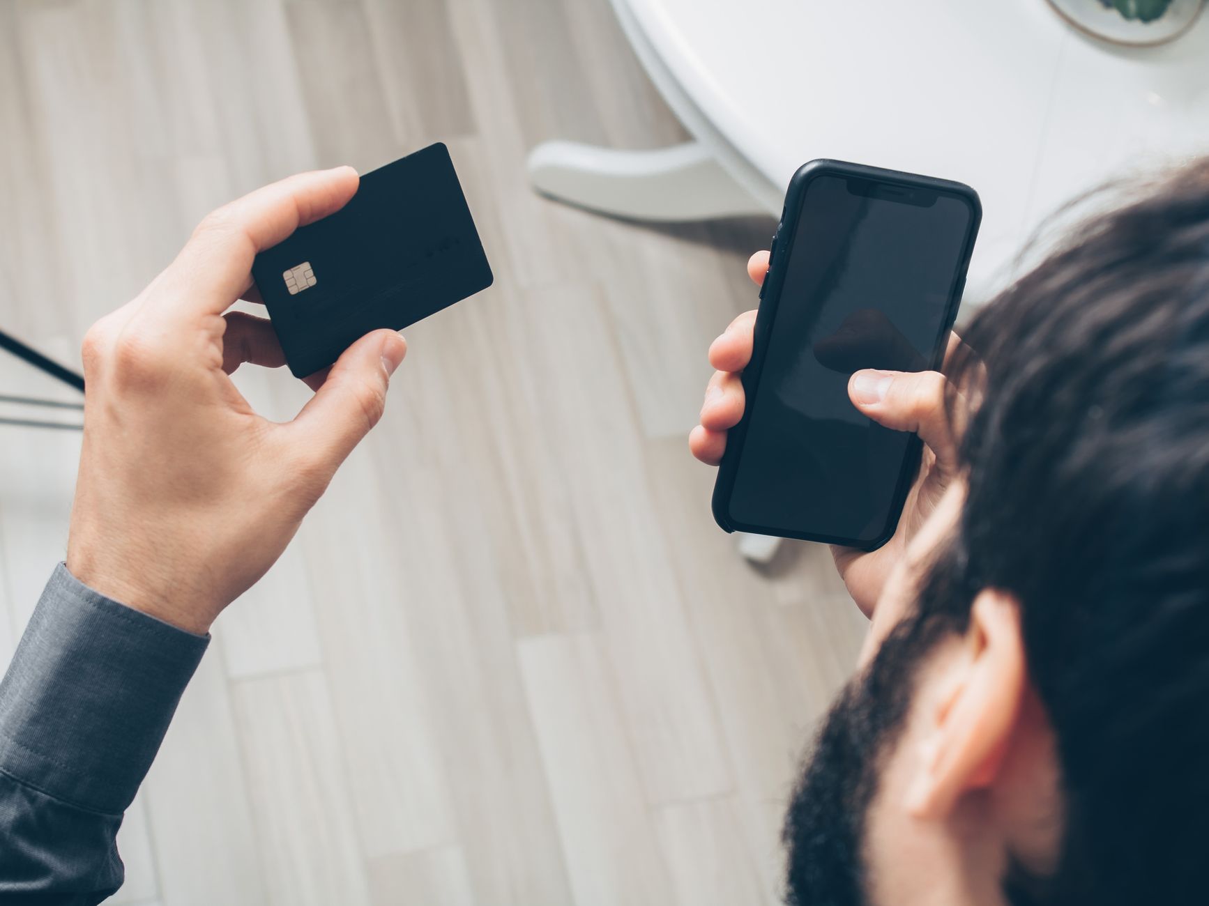 Personne finalisant un paiement en ligne sur son smartphone avec une carte bancaire