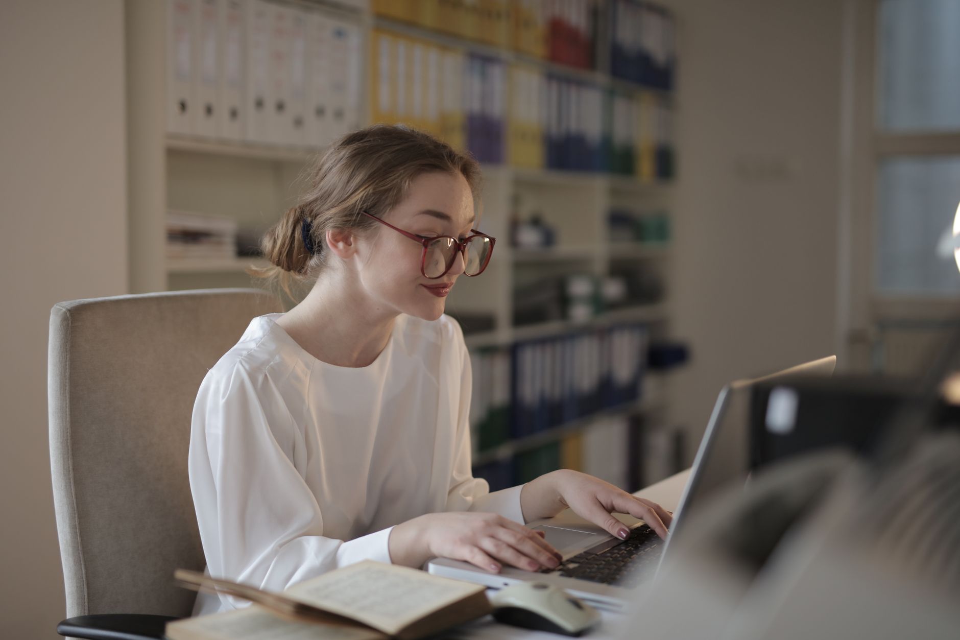 Une femme concentrée sur son ordinateur portable à un bureau, en train de travailler sur ses campagnes email